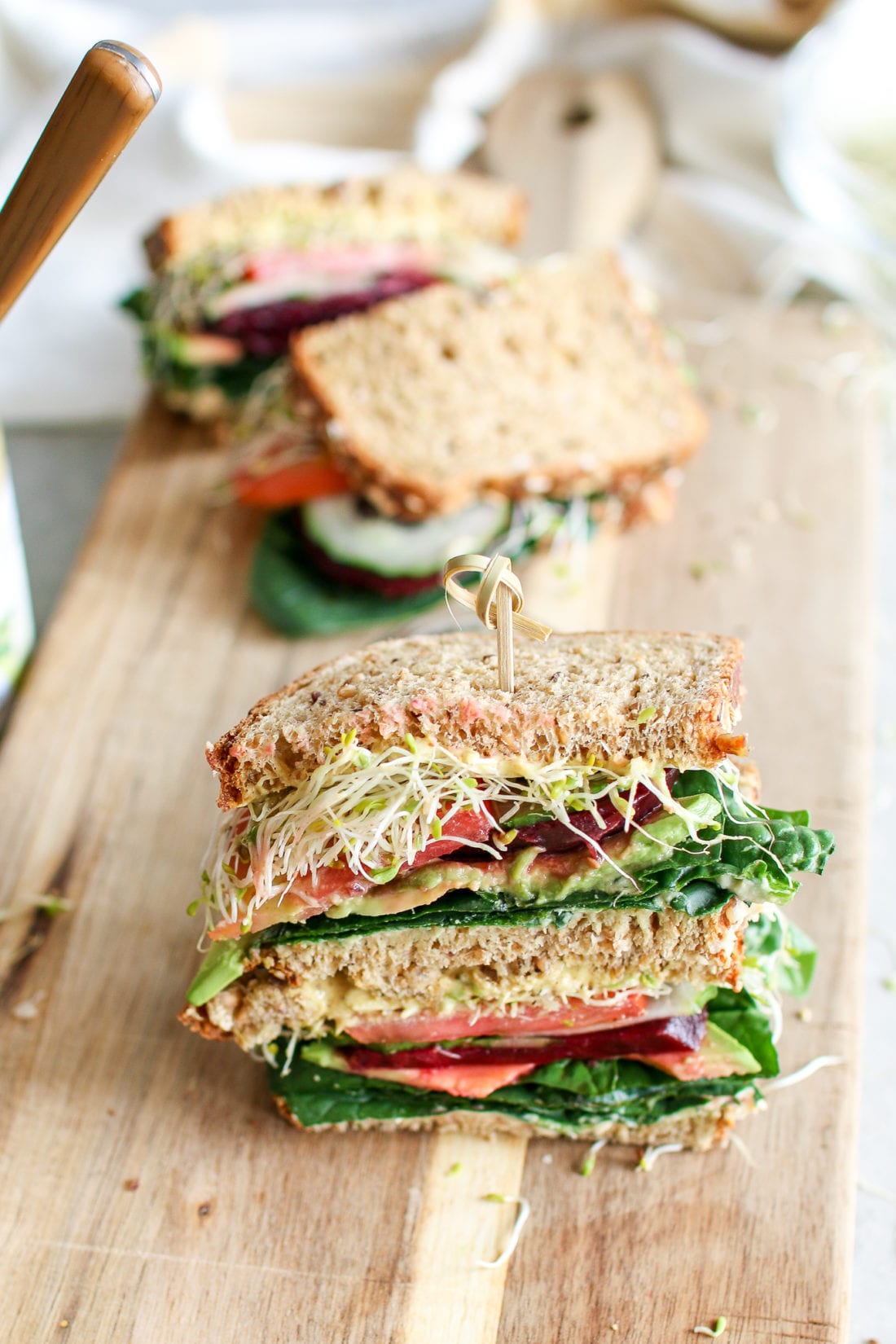 A colourful veggie sandwich stacked with fresh spinach, creamy avocado, crunchy cucumbers, tomatoes, beets and microgreens, smooshed between your favourite bread and smothered in caramelized onion hummus and creamy aioli. The ultimate sammy!