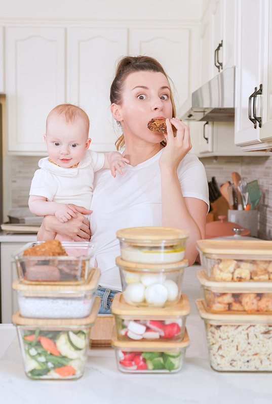 Mom holding her baby and eating meal prepped food