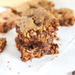 peanut butter cookie bars piled on top of each other on a white table
