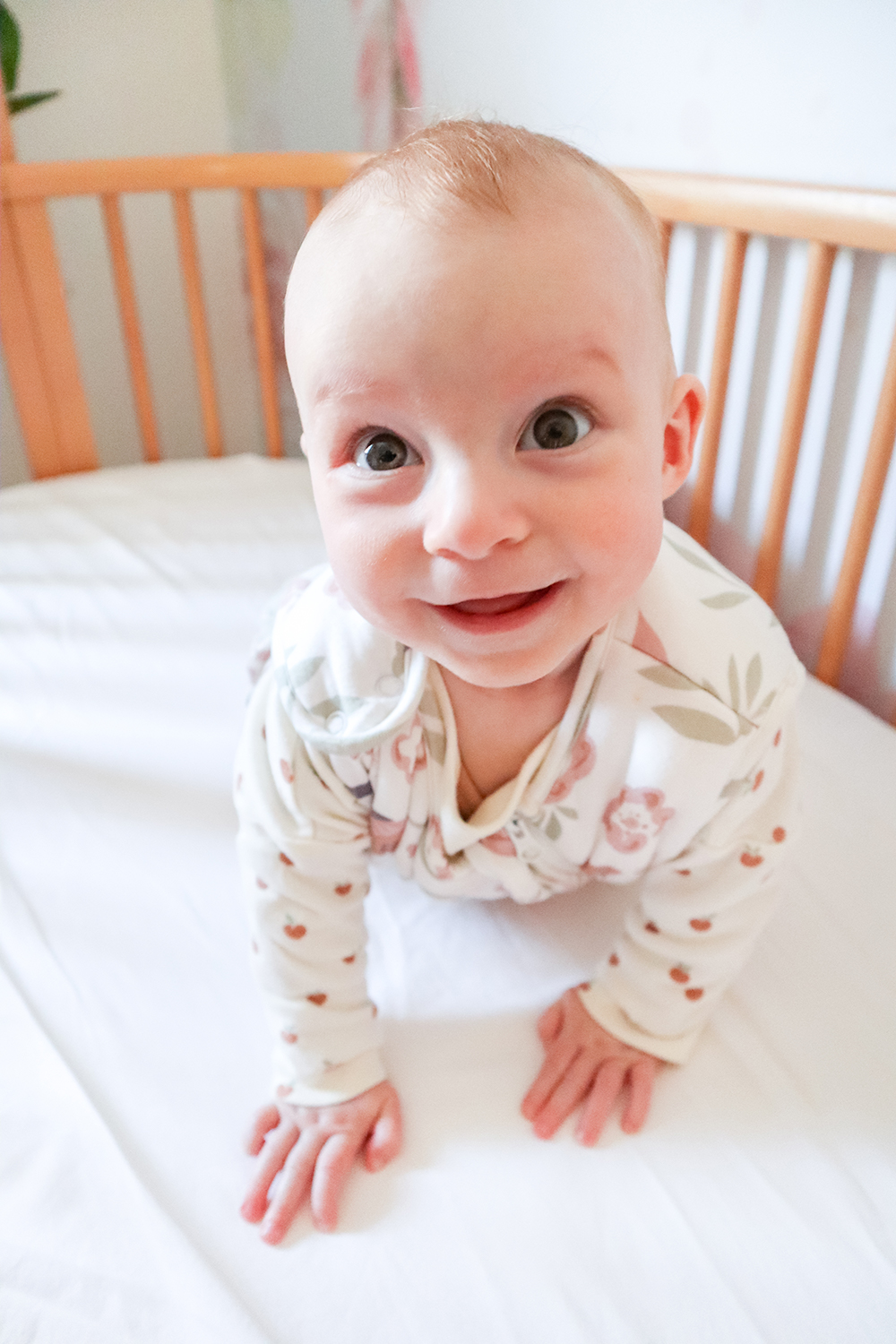 a 6 month old baby on her hands and knees in her cot