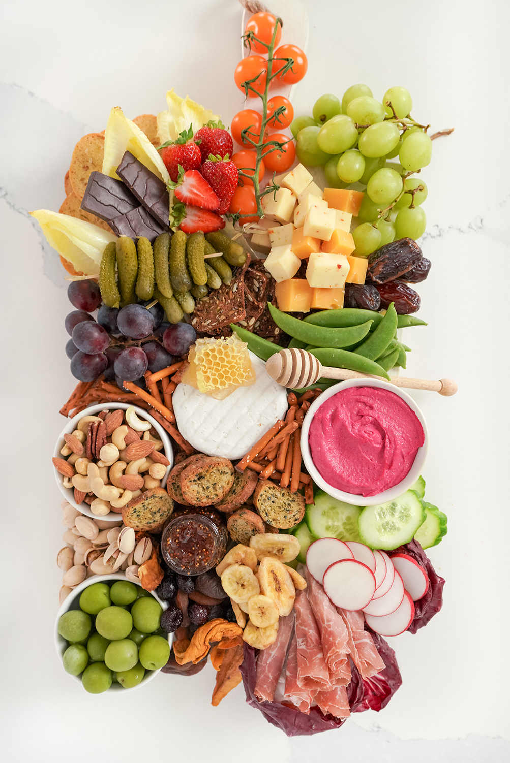 a grazing board containing fruits, veggies, cheese, crackers and cured meat