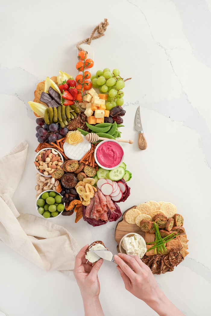 a charcuterie board with a variety of fruits, veggies, cheeses, meats and crackers