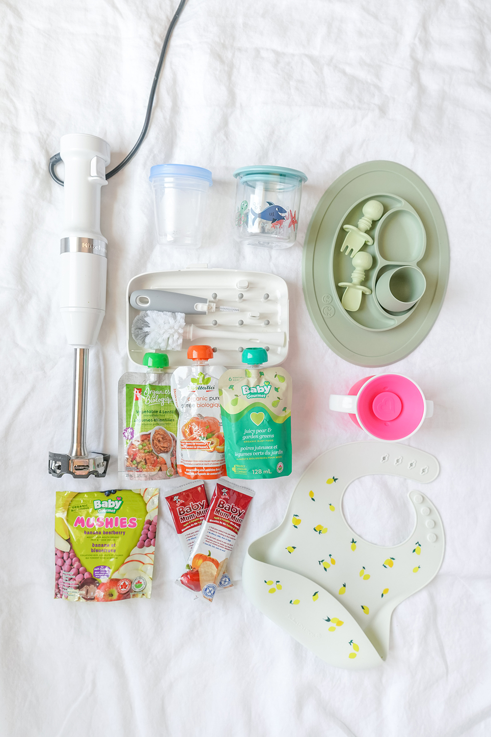 a flat lay of baby food essentials on a white sheet