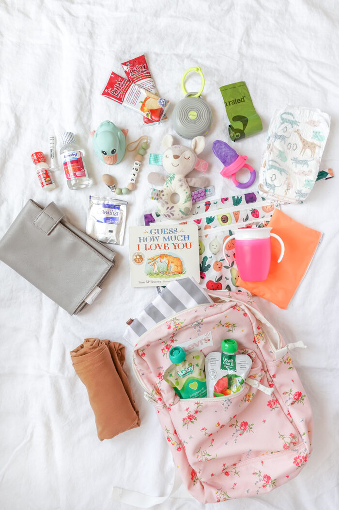 flatlay of baby travel essentials on a white sheet