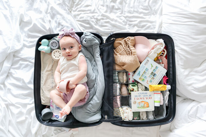 a baby in a suitcase on a white sheet