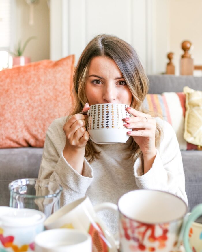 woman with brown hair drinking herbal coffee out of a black and white mug