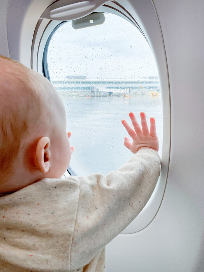 baby with her hand on the window of a plane