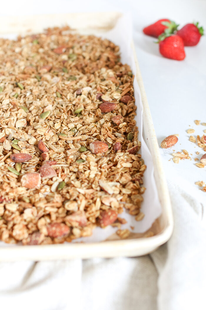 homemade granola in a white tray with strawberries next to it