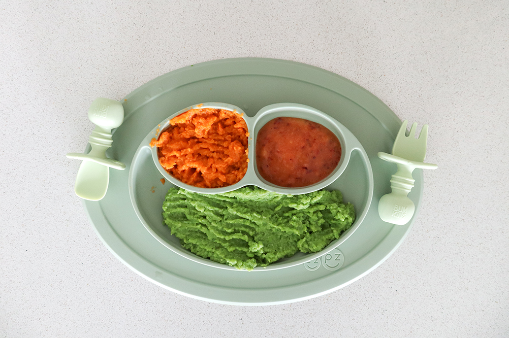 Baby food consisting of avocado, sweet potato and peaches on a green plate