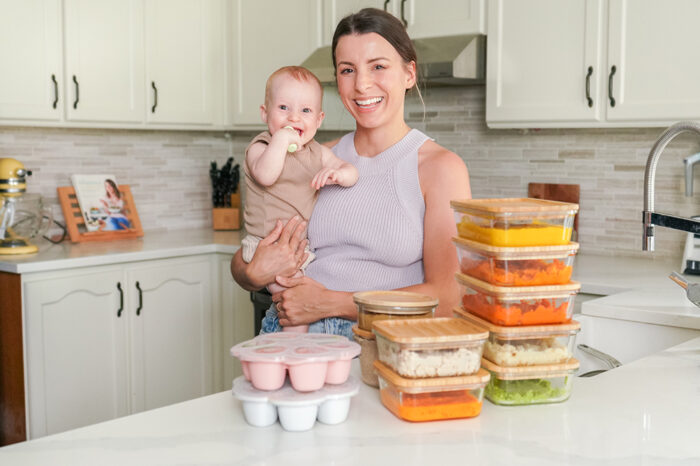 mother holding her baby in front of meal prepped baby food