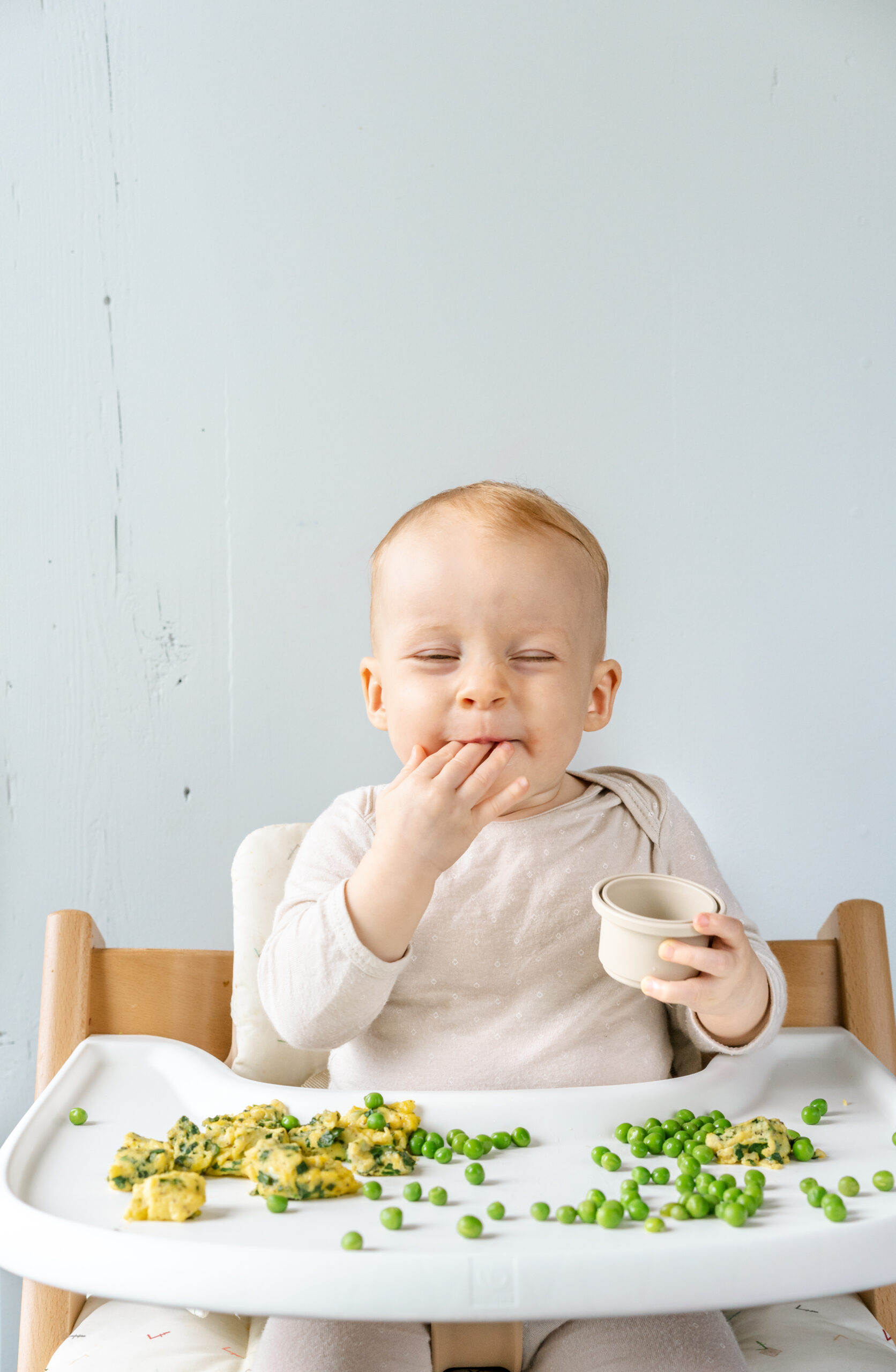 baby enjoying food in high chair