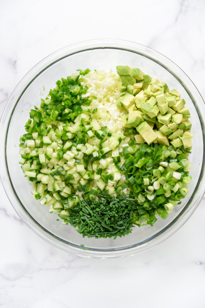a bowl of ingredients to make TikTok's green goddess salad sitting on a marble countertop