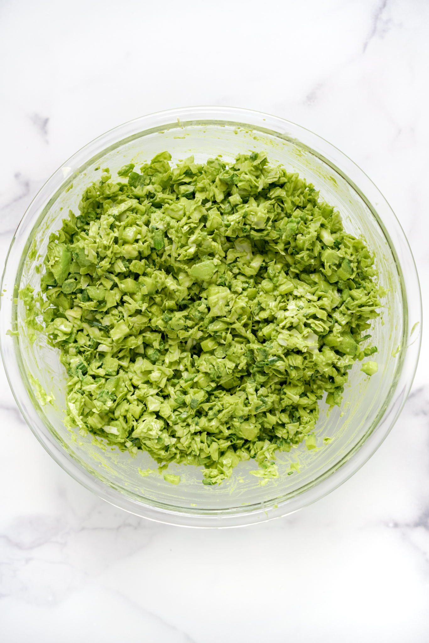 a bowl of green goddess salad on a marble countertop