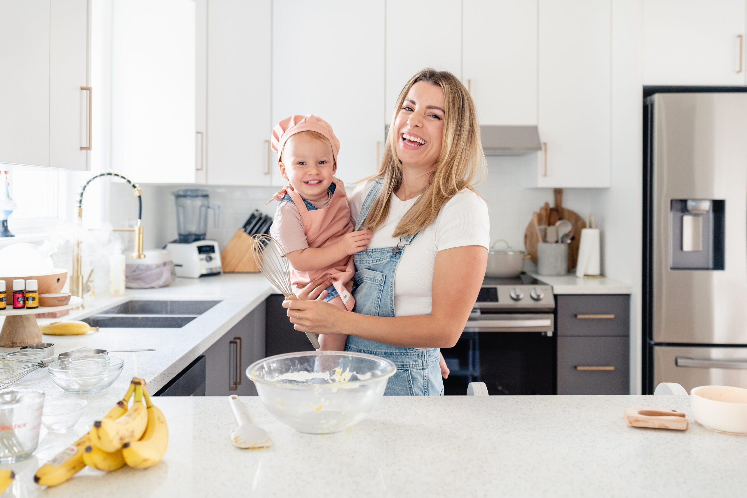 mom holding daughter in kitchen ready to bake