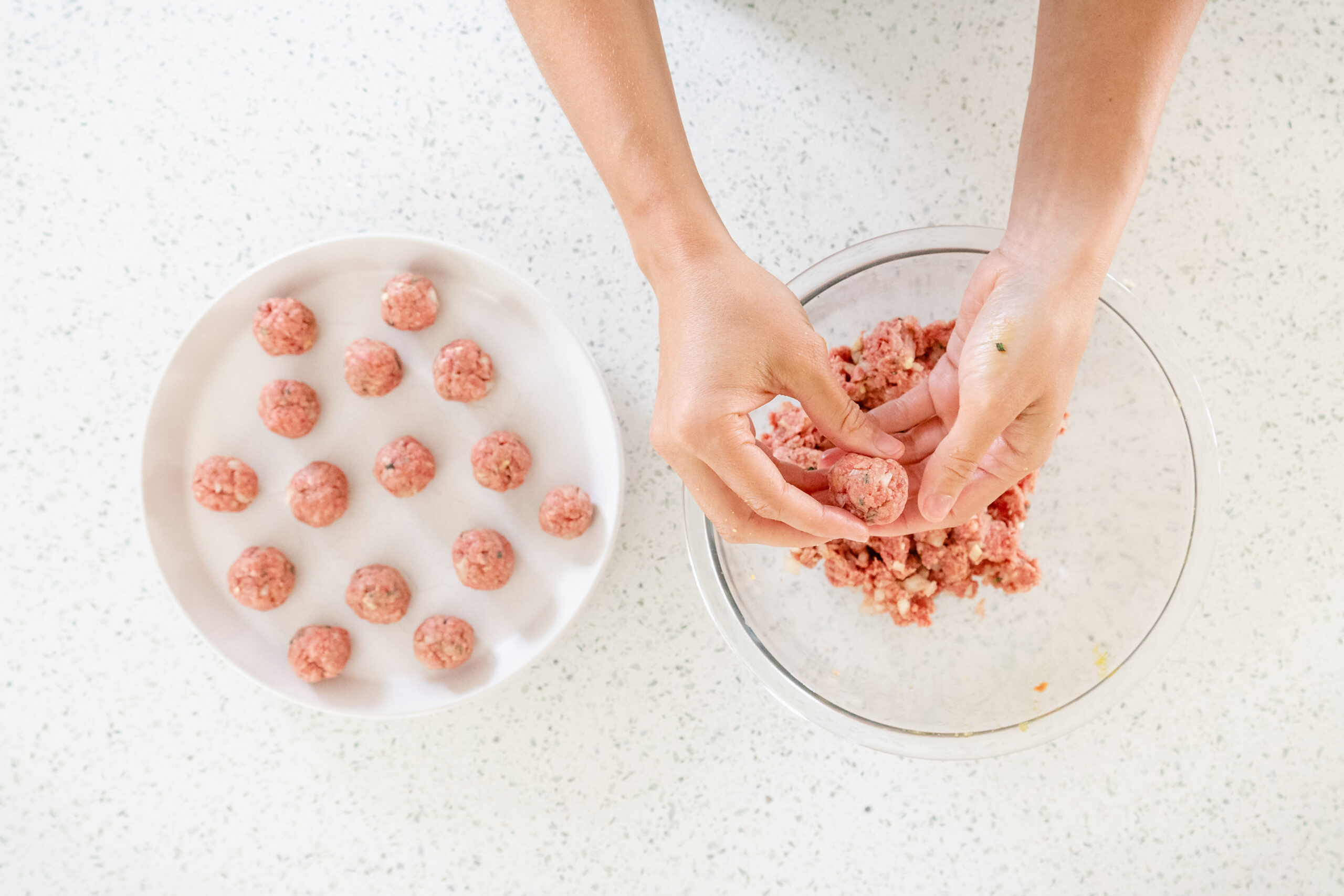 hands rolling meat mixture into meatballs