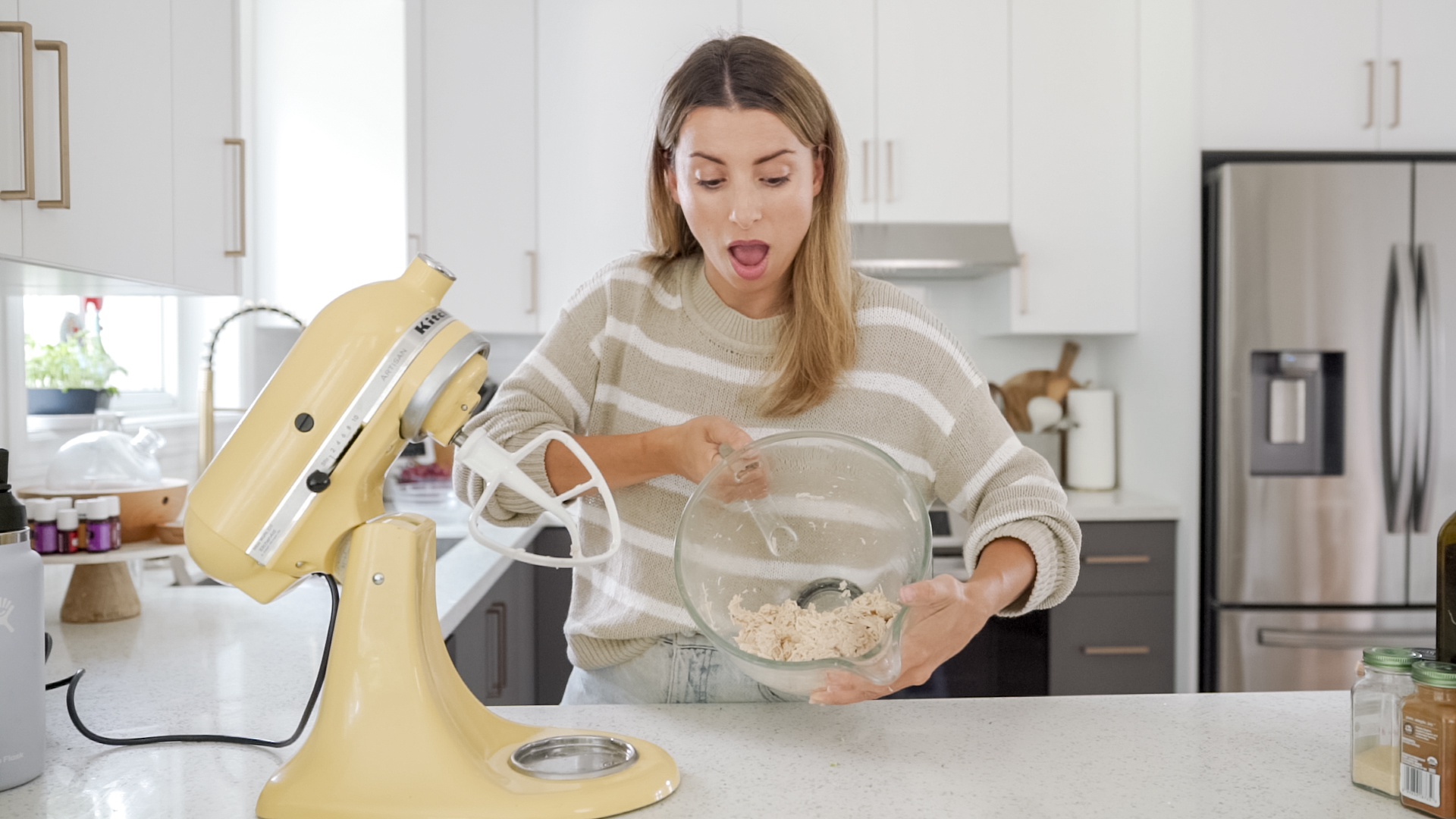 woman holding stand mixer bowl with shredded chicken